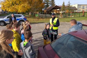 policjant z dziećmi prowadzi kontrolę , dziewczynka wręcza kierowcy sok z cytryny