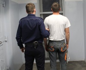 umundurowany policjant prowadzi zatrzymanego do celi w wieluńskiej komendzie
