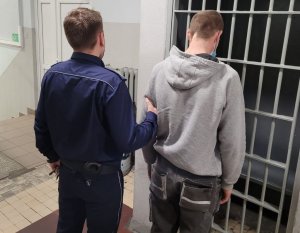 umundurowany policjant prowadzi zatrzymanego po korytarzu w wieluńskiej komendzie