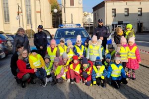 policjanci na parkingu na tle radiowozu pozują z dziećmi do zdjęcia