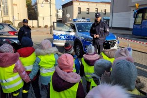 policjanci na parkingu prezentują dzieciom radiowóz