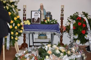 urna na katafalku, obok zdjęcie zmarłego wokół wieńce