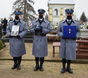 na cmentarzu stoi asysta z odznaczeniem, czapką i zdjęciem