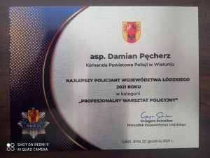 statuetka dla asp. Damiana Pęcherza dla najlepszego policjanta 2021 roku województwa łódzkiego wyróżnionego w kategorii najlepszy warsztat policyjny