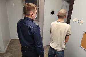 policjant prowadzi zatrzymanego do celi
