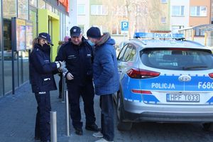 policjanci przed sklepem rozdają elementy odblaskowe i zawieszki zapachowe przechodniom