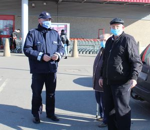 policjant przed sklepem rozdają elementy odblaskowe i zawieszki zapachowe przechodniom