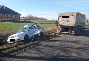 uszkodzony osobowy pojazd stojący w rowie oraz ciężarówka stojąca na poboczu