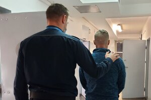 policjant prowadzi zatrzymanego do celi