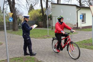 dziecko na terenie miasteczka ruchu drogowego jedzie na rowerze w kasku, policjantka chodzi i ocenia jego jazdę
