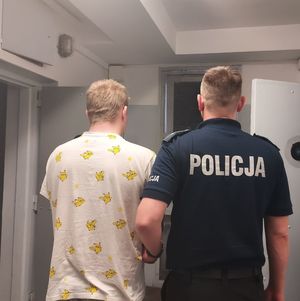 policjant prowadzi zatrzymanego do celi