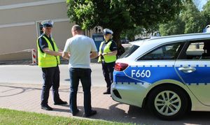 radiowóz, obok stoją policjanci rozmawiający z pieszym