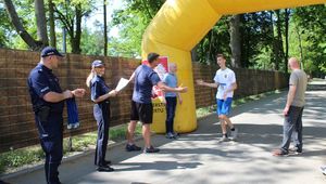 organizatorzy biegu wręczają medale przybiegającym zawodnikom na metę