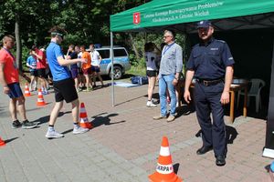 osoby pokonujące tor przeszkód w alkogogalch , w tle policjanci, zaproszeni goście i uczestnicy imprezy