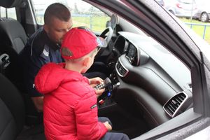 zdjęcie przedstawiające policjanta oraz uczestnika imprezy zorganizowanej z okazji Dnia Dziecka przez UM Wieluń oraz WDK w dniu 28 maja 2022 roku w policyjnym radiowozie