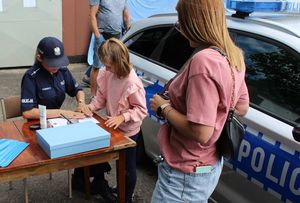 zdjęcie przedstawiające policjantkę wykonującą pamiątkową daktyloskopię oraz uczestników &quot;EMDEKOLADY&quot;