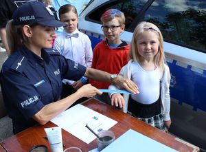 zdjęcie przedstawiające policjantkę wręczającą element odblaskowy uczestnikom &quot;EMDEKOLADY&quot;