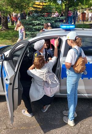 zdjęcie przedstawiające policjanta prezentującego radiowóz uczestnikom &quot;EMDEKOLADY&quot;