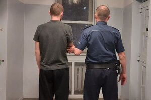 policjant prowadzi zatrzymanego do celi