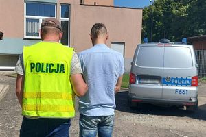 Policjant prowadzi zatrzymanego.