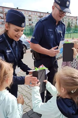 dzieci wręczają policjantom zrobione prace plastyczne