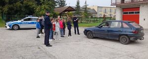 policjanci wspólnie z dziećmi prowadzą kontrolę drogową, mundurowi zatrzymali do sprawdzenia pojazd