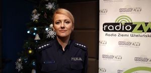 Policjantka w studiu radiowym stoi przy choince.