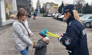 Policjantka wręcza odblask kobiecie z dzieckiem.