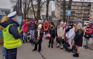 policjant trzyma w ręku odblask rozmawia z dziećmi.