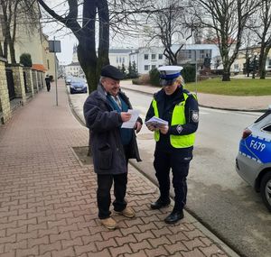 Policjantka wręcza przechodniom odblaski.