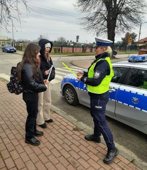 Policjantka wręcza przechodniom odblaski.