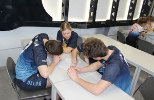 Drużyna czteroosobowa uczniów siedzi w ławce i pisze test.