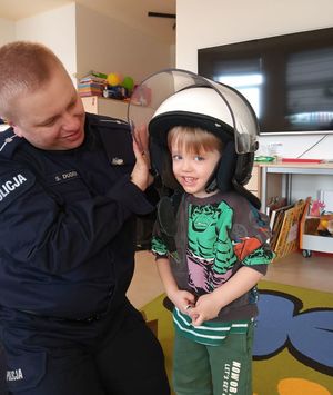 Policjant założył dziecku na głowę hełm używany przez policjantów podczas zabezpieczeń imprez masowych.