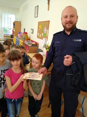 dzieci wręczają policjantowi podziękowanie.