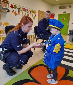 Policjantka pokazuje chłopcu kajdanki.