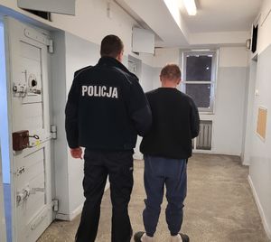 Policjant prowadzi zatrzymanego do celi.