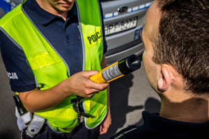 Policjant weryfikuje urządzeniem alcoblow stan trzeźwości mężczyzny.