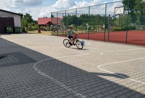 Chłopiec jedzie na rowerze po torze przeszkód, zdaje praktyczny egzamin na kartę rowerową.