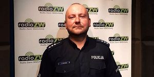 Policjant umundurowany w studiu radiowym, wizerunek od pasa w górę.