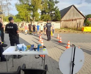 Policjanci w trakcie pikniku na wystawionym stoisku promują bezpieczeństwo, rozmawiają z uczestnikami.