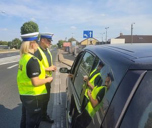 Policjanci przeprowadzają kontrolę drogową samochodu.