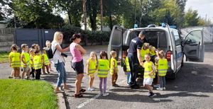 Dziedziniec wewnętrzny wieluńskiej komendy policji. Policjanci prezentują dzieciom radiowóz.