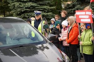 Policjantka wspólnie z uczniami prowadzą kontrolę drogową.