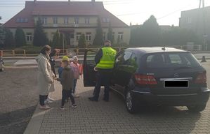 Policjant wspólnie z  uczniami prowadzą kontrolę drogową.