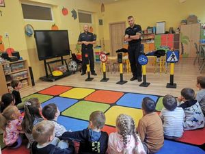 Policjanci w sali z przedszkolakami prowadzą pogadankę.