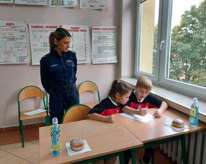 Policjantka nadzoruje pisanie testu przez uczestników konkursu.