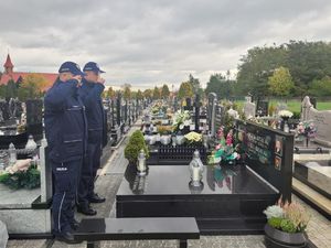 I Zastępca Komendanta Powiatowego Policji w Wieluniu i Naczelnik Prewencji oddają hołd na cmentarzu przed pomnikiem zmarłego policjanta.