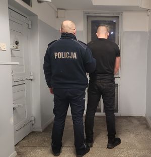 Policjant prowadzi zatrzymanego do celi.