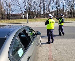 Policjanci stoją na drodze nadzorując ruch.