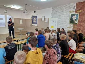 zdjęcie przedstawiające policjanta prowadzącego pogadankę z dziećmi w Ostrówku